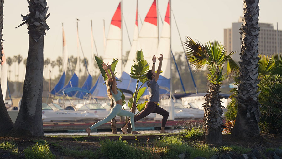 Two individuals doing yoga with marina in background