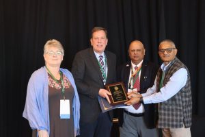 Photo of the individual holding an award with three colleagues standing next to the individual.