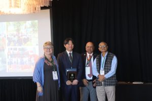 Photo of individual holding an award with 3 colleagues standing next to the individual.