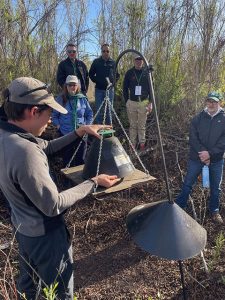 An individual tending to a pest trap with bystanders watching.