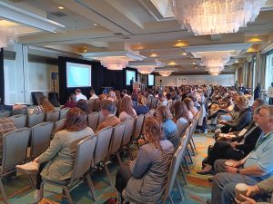 Conference attendees seated in theater style rows.