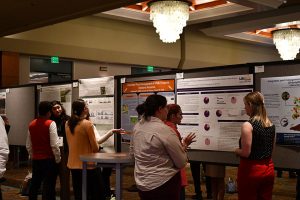 Attendees speaking with individual poster authors at academic poster session.