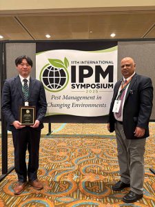 Two men standing on either side of a poster with a conference logo.